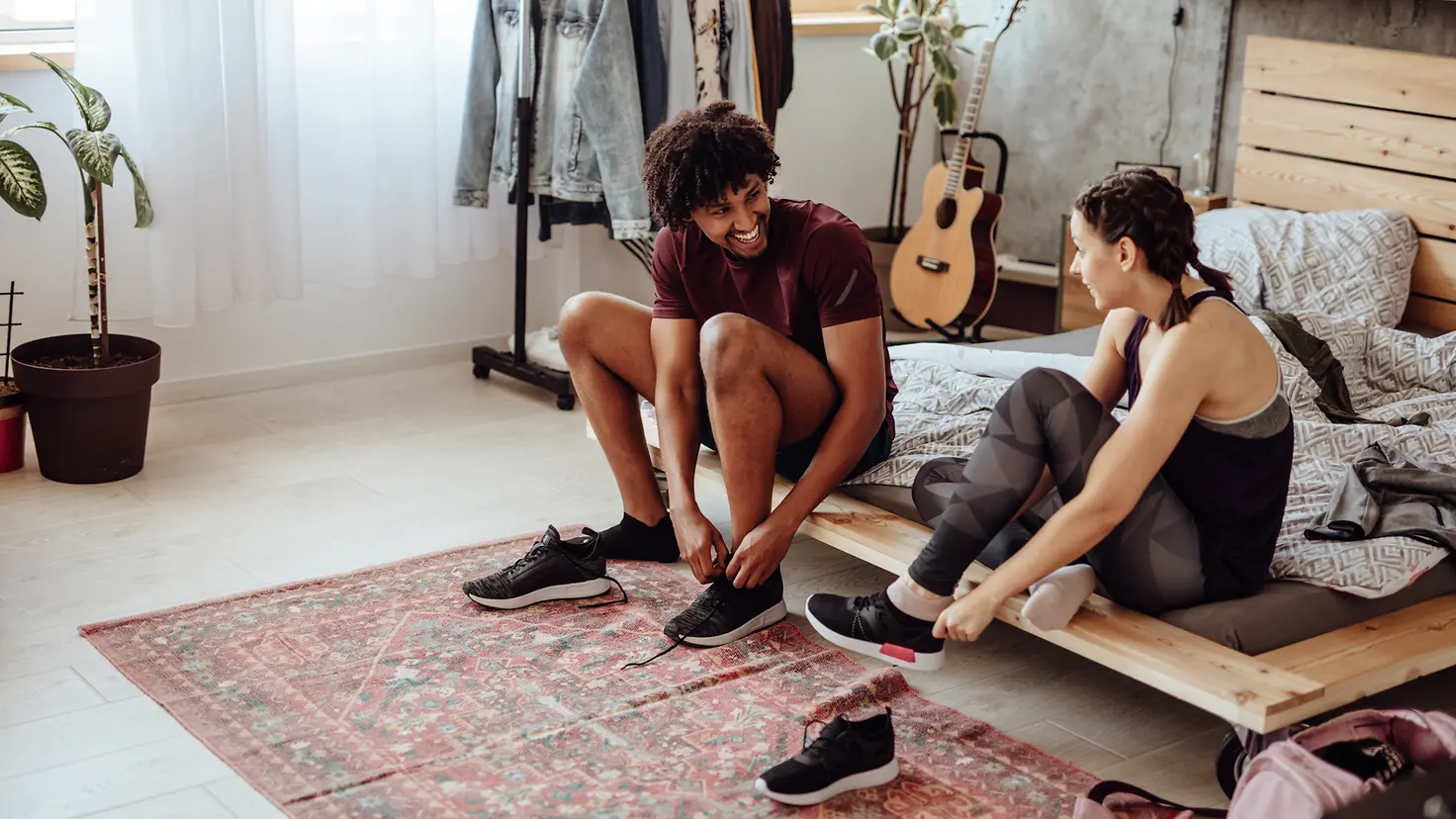 Ein junges Paar zieht sich Sportschuhe an